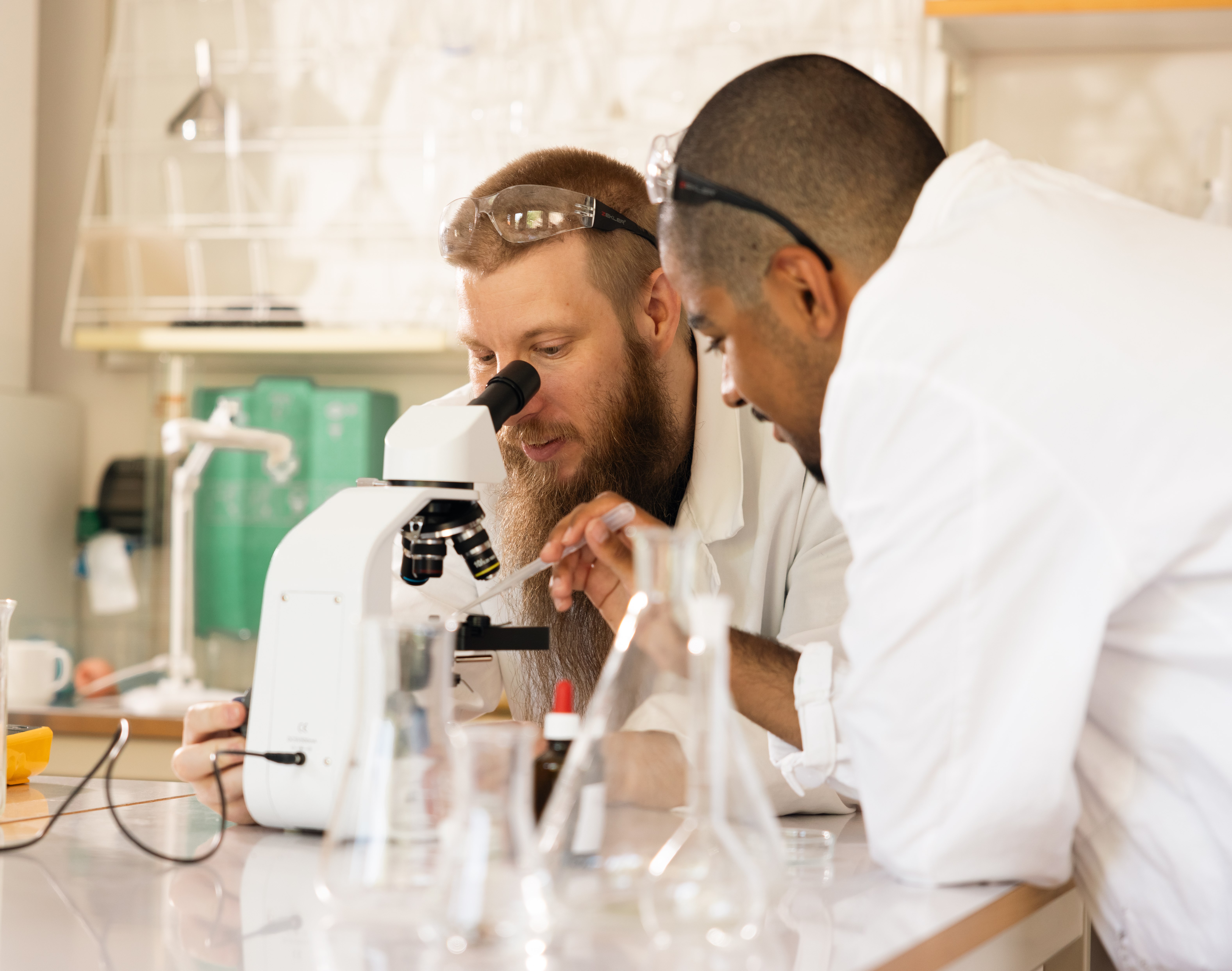 Två deltagare tittar i ett mikroskåp